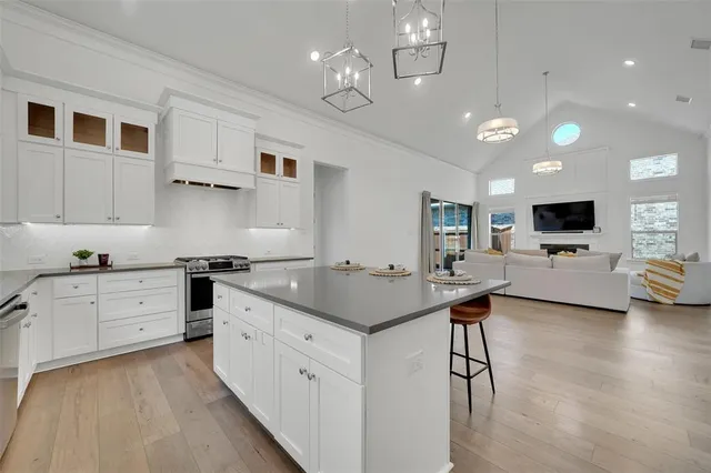 a kitchen with stainless steel appliances kitchen island granite countertop a stove top oven a sink dishwasher and a refrigerator with wooden floor