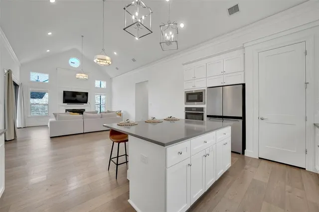 a kitchen with stainless steel appliances granite countertop a sink a stove a dining table and chairs