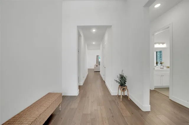 a view of a hallway with wooden floor and a bathroom