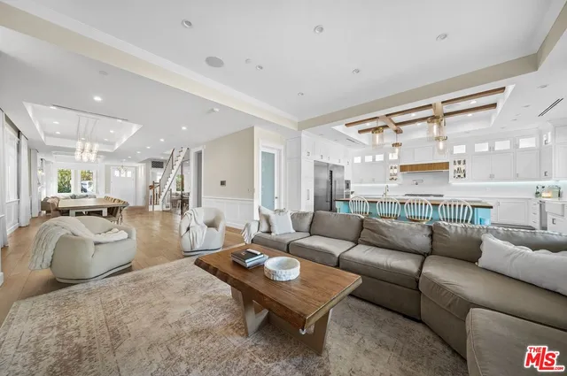 a living room with furniture a rug kitchen view and a large window