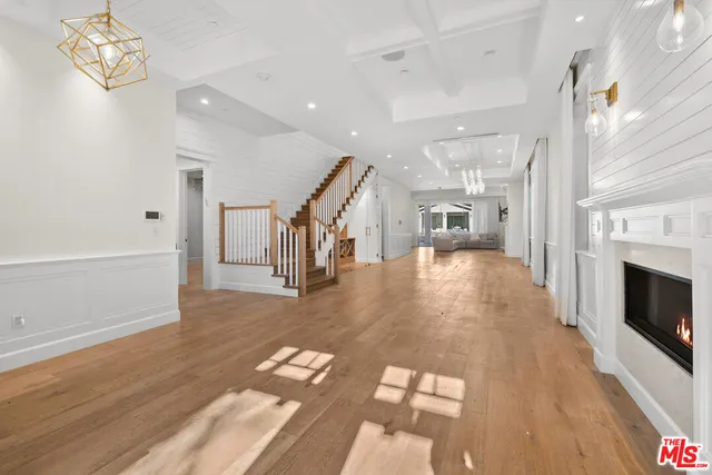 a hallway with wooden floor fireplace and windows