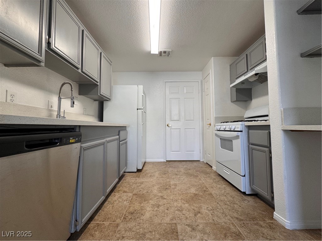 9975 Peace Way, Unit 1140 Las Vegas, NV 89147 - Photo 3 of 23 Kitchen with stove, dishwashing machine, visible vents, gray cabinets, and fridge