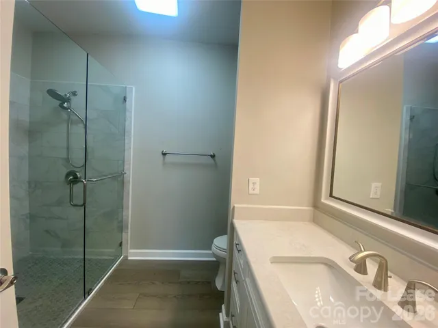 a bathroom with a granite countertop sink a toilet and shower