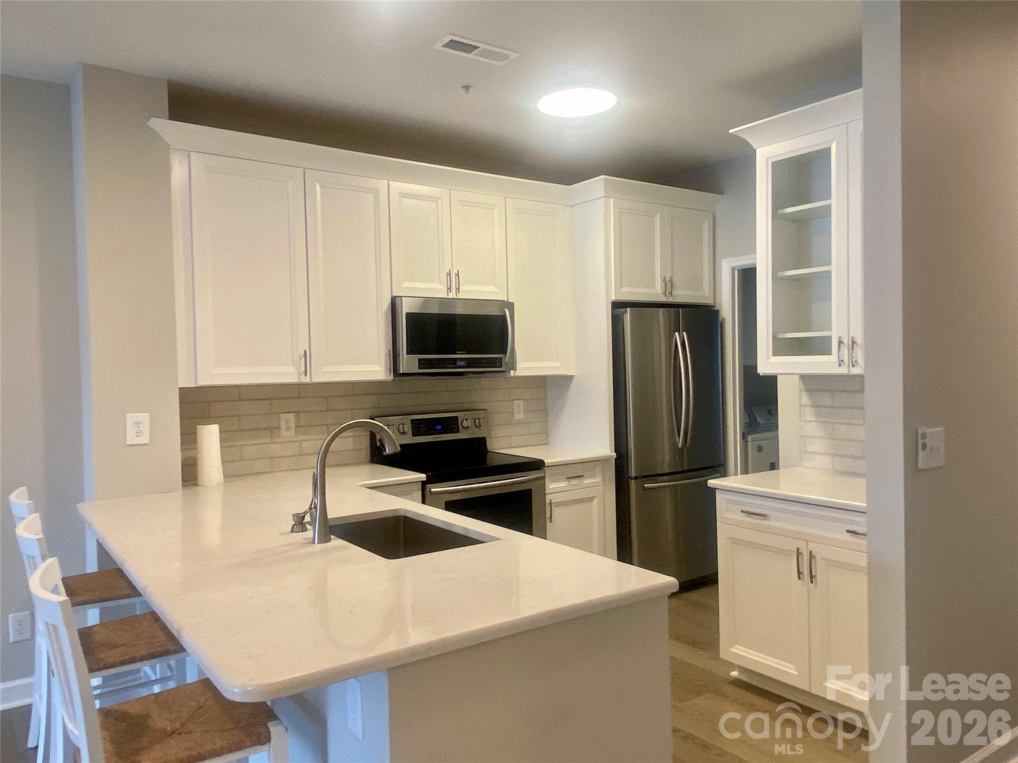 920 Jetton Street, Unit 49 Davidson, NC 28036 - Photo 8 of 33 a kitchen with a sink a microwave a refrigerator and cabinets