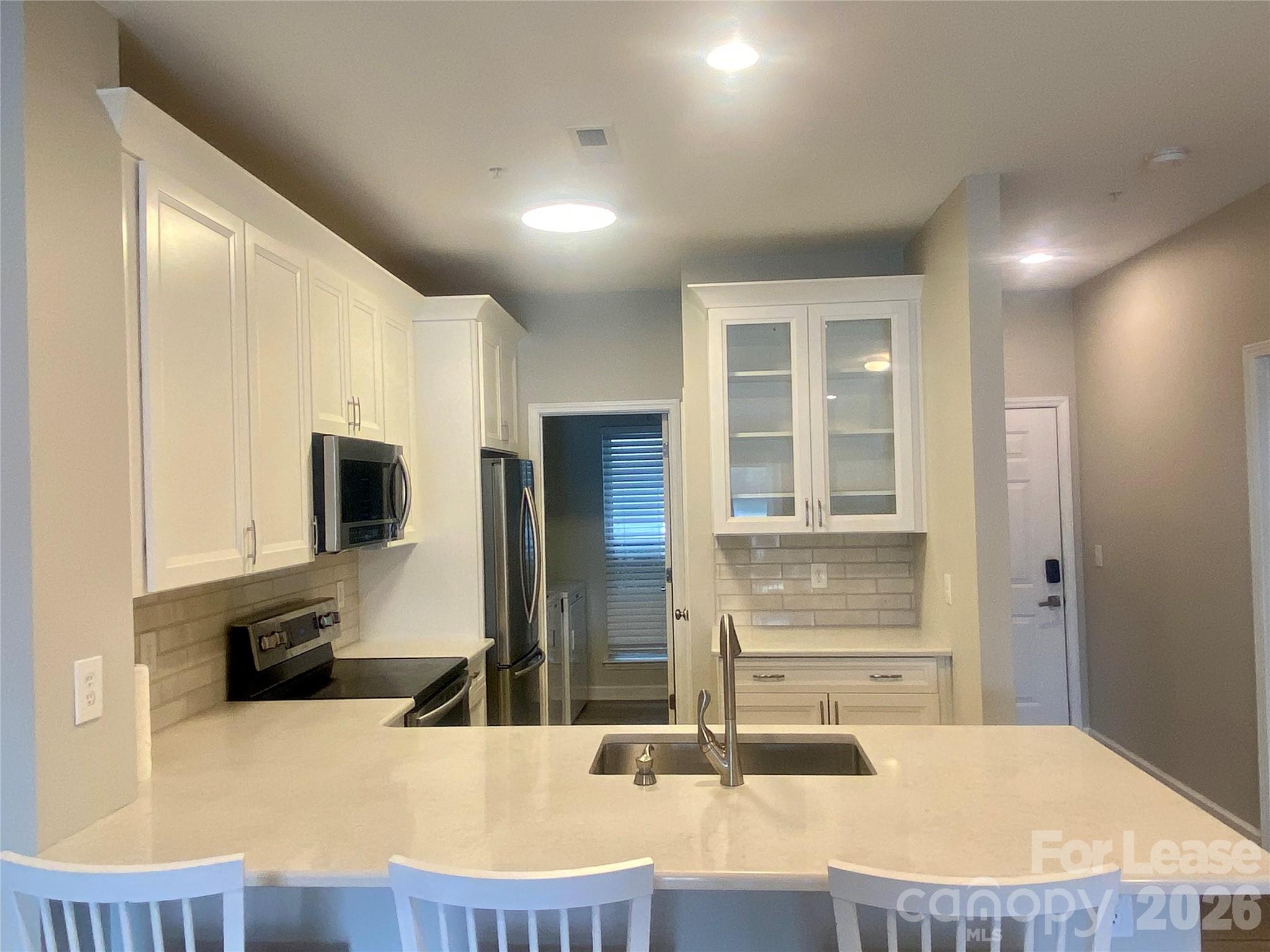 920 Jetton Street, Unit 49 Davidson, NC 28036 - Photo 9 of 33 a kitchen with kitchen island granite countertop a sink and a refrigerator