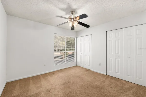 an empty room with windows and fan