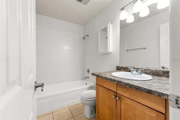 a bathroom with a granite countertop sink a toilet a mirror and bathtub