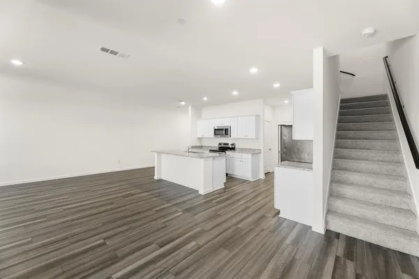 a view of kitchen living room with cabinets wooden floor and stainless steel appliances