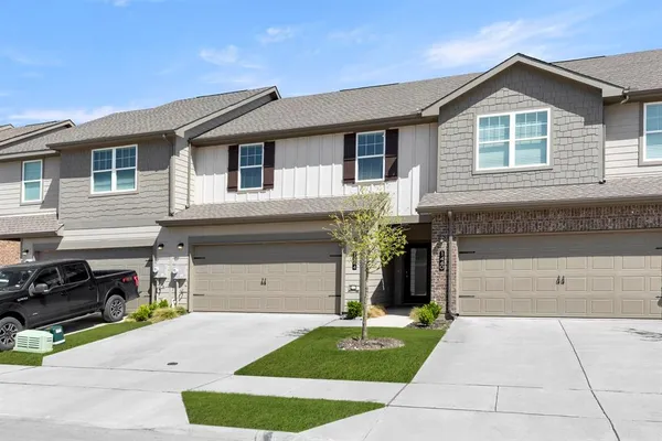 a front view of a house with a garden and trees