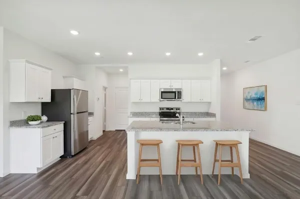 a kitchen with stainless steel appliances kitchen island granite countertop a table chairs stove and refrigerator