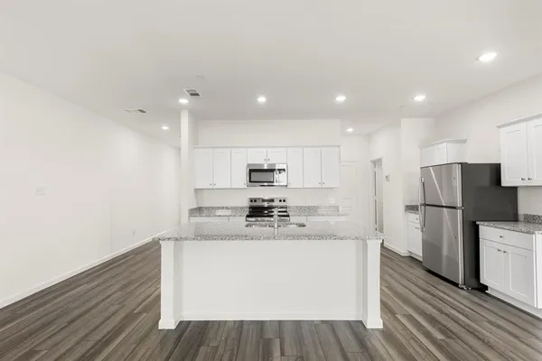 a kitchen with stainless steel appliances a white refrigerator a sink dishwasher a oven with white cabinets and wooden floor