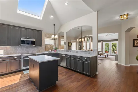 a kitchen with stainless steel appliances granite countertop wooden cabinets a sink dishwasher a stove and a refrigerator