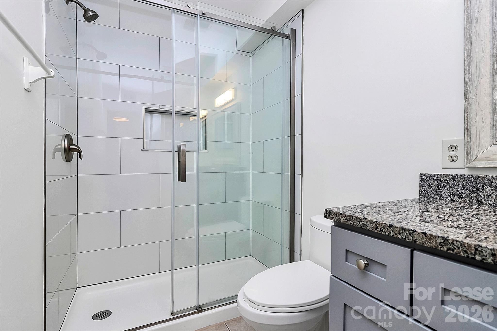 430 Queens Road, Unit 711 Charlotte, NC 28204 - Photo 13 of 20 a bathroom with a granite countertop shower a toilet and sink