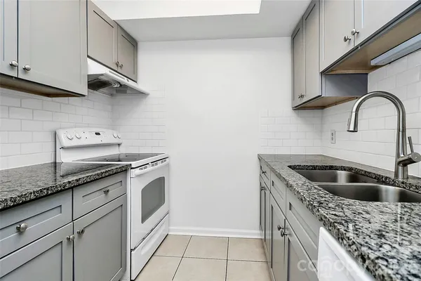a kitchen with granite countertop a sink and a stove top oven