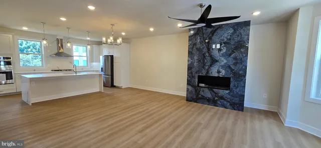 a view of a kitchen and an empty room with wooden floor and a kitchen