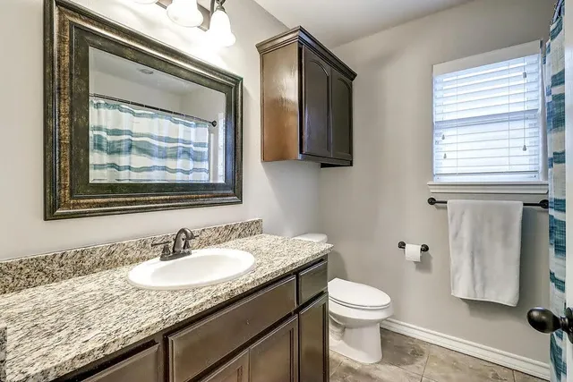 a bathroom with a granite countertop sink toilet and mirror
