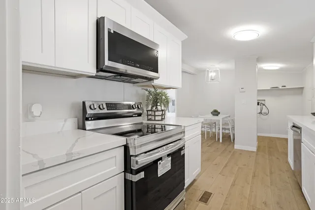 a kitchen with stainless steel appliances a stove a microwave and white cabinets