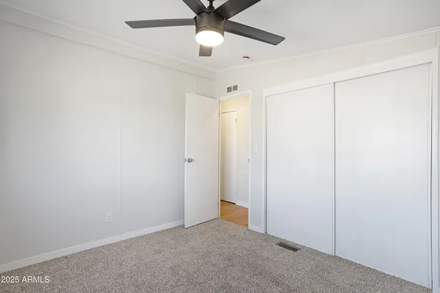 an empty room with closet and a chandelier fan