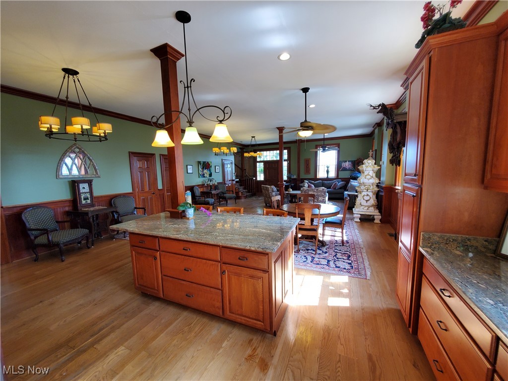 150 Main Street Hayesville, OH 44805 - Photo 9 of 50 Kitchen featuring brown cabinets, dark stone countertops, wainscoting, ornamental molding, and a center island.