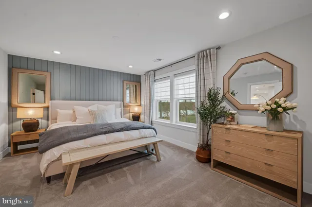 a spacious bedroom with a bed a mirror and a large window