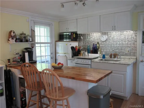 a kitchen with stainless steel appliances granite countertop a table chairs sink refrigerator and window