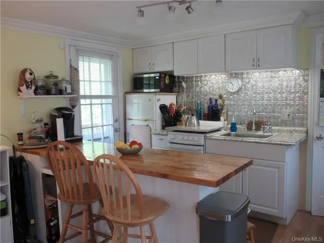 a kitchen with stainless steel appliances granite countertop a table chairs sink refrigerator and window