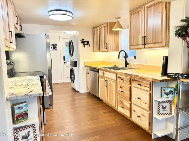 a large kitchen with stainless steel appliances a stove a sink dishwasher and cabinets with wooden floor