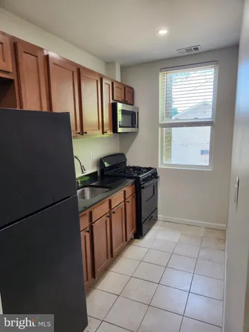 a kitchen with granite countertop a refrigerator and a stove top oven