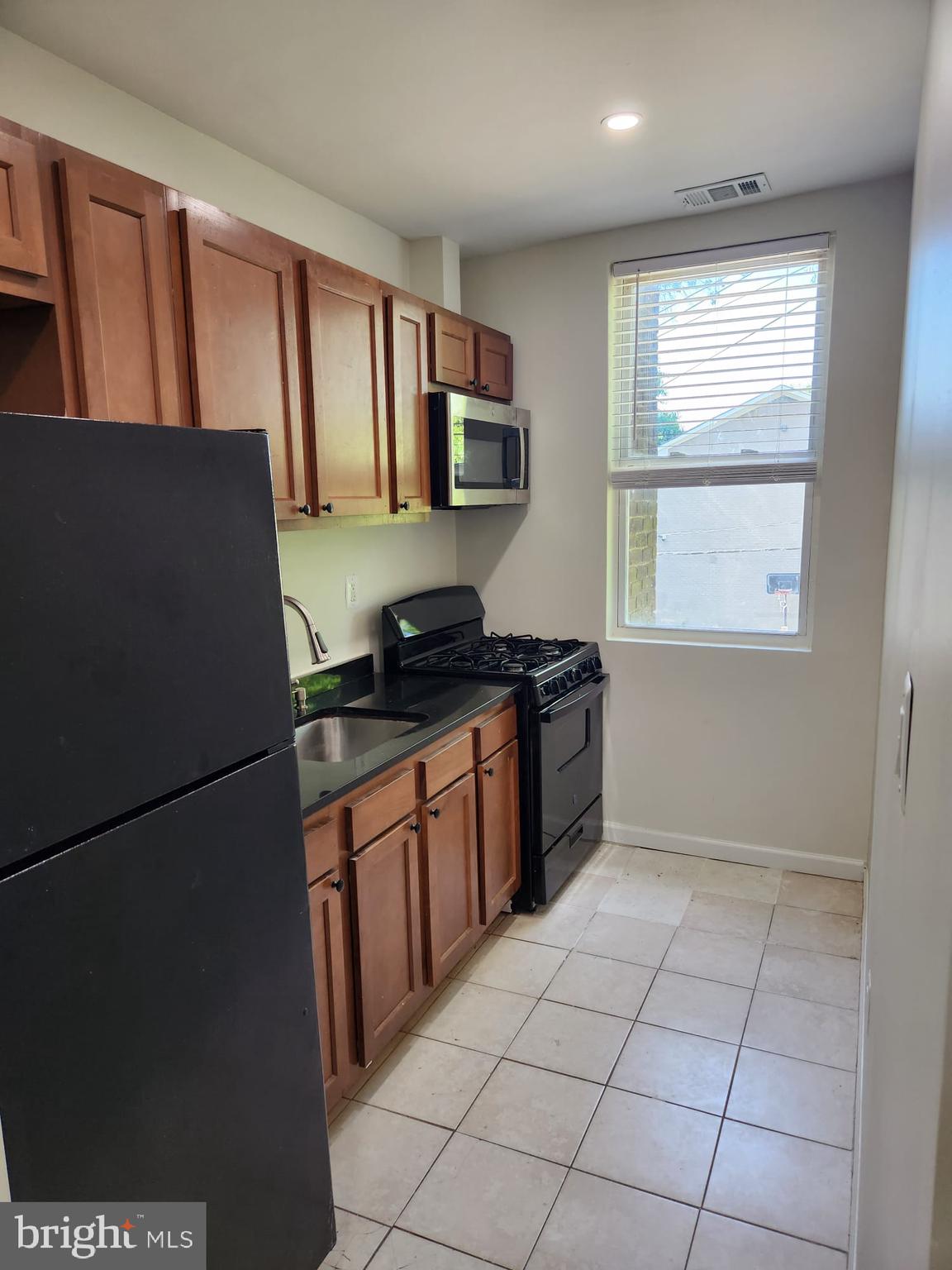 a kitchen with granite countertop a refrigerator and a stove top oven