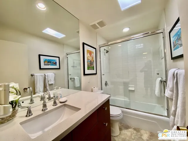 a bathroom with a granite countertop sink a toilet a mirror and shower