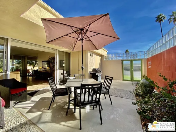 a view of a patio with table and chairs potted plants and floor to ceiling window