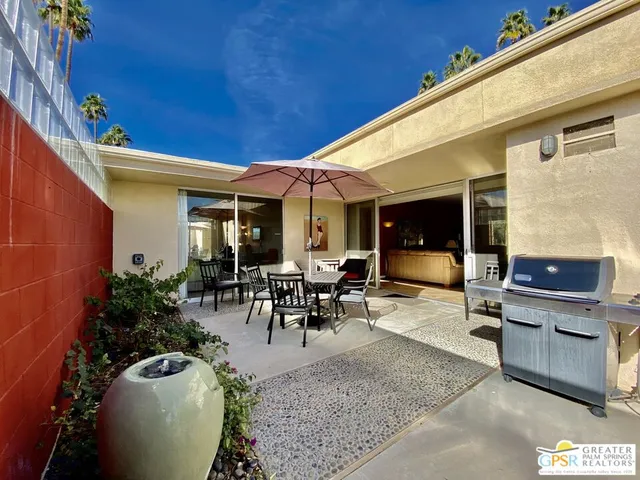 a view of a patio with table and chairs potted plants and floor to ceiling window