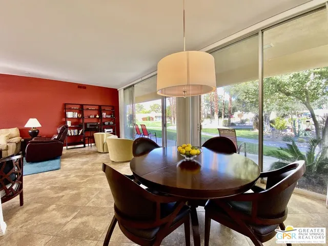 a view of a dining room with furniture a chandelier and large windows
