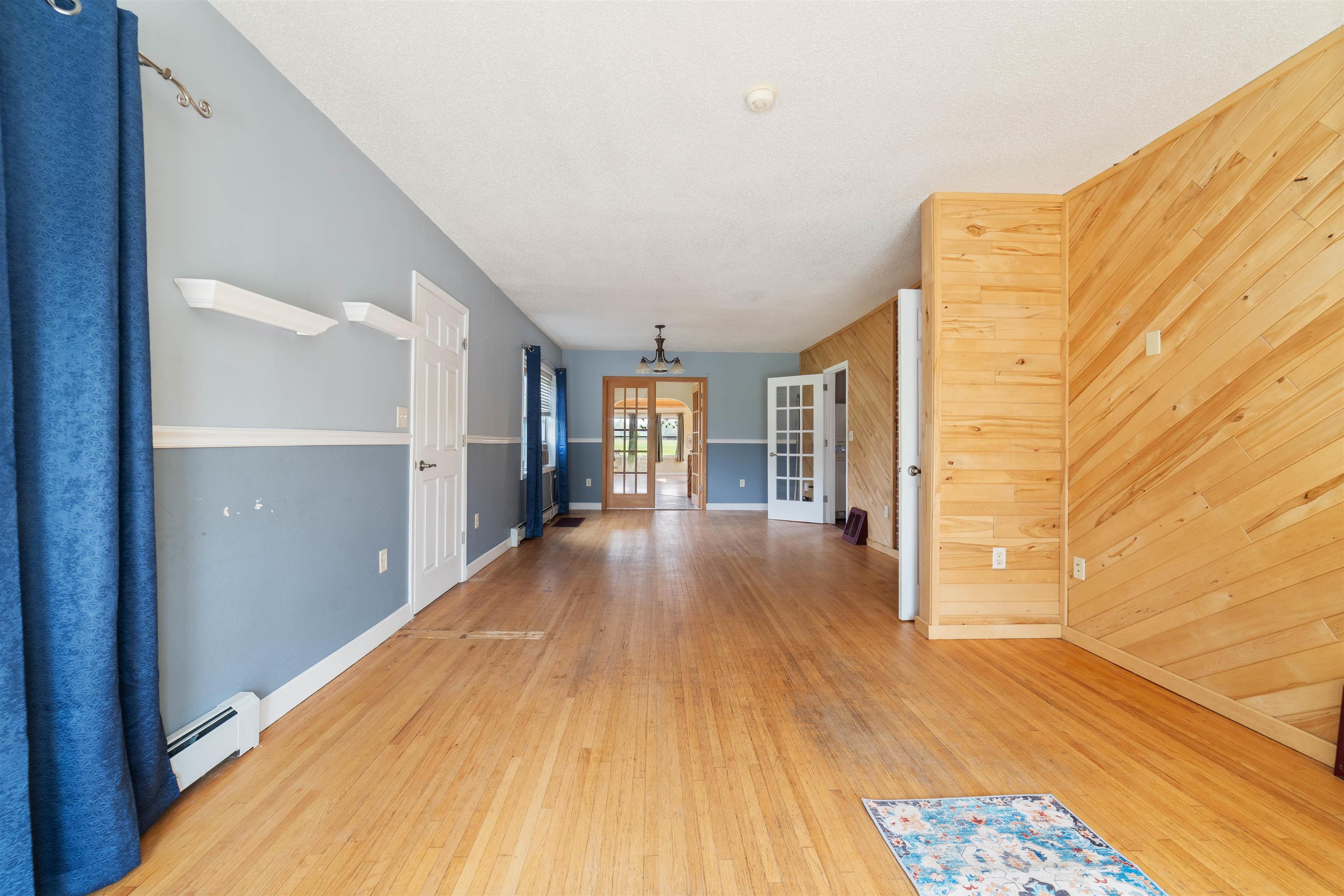 9372 McCamus Road Brookston, MN 55711 - Photo 17 of 49 Corridor with wooden walls, french doors, light wood-type flooring, and a baseboard radiator