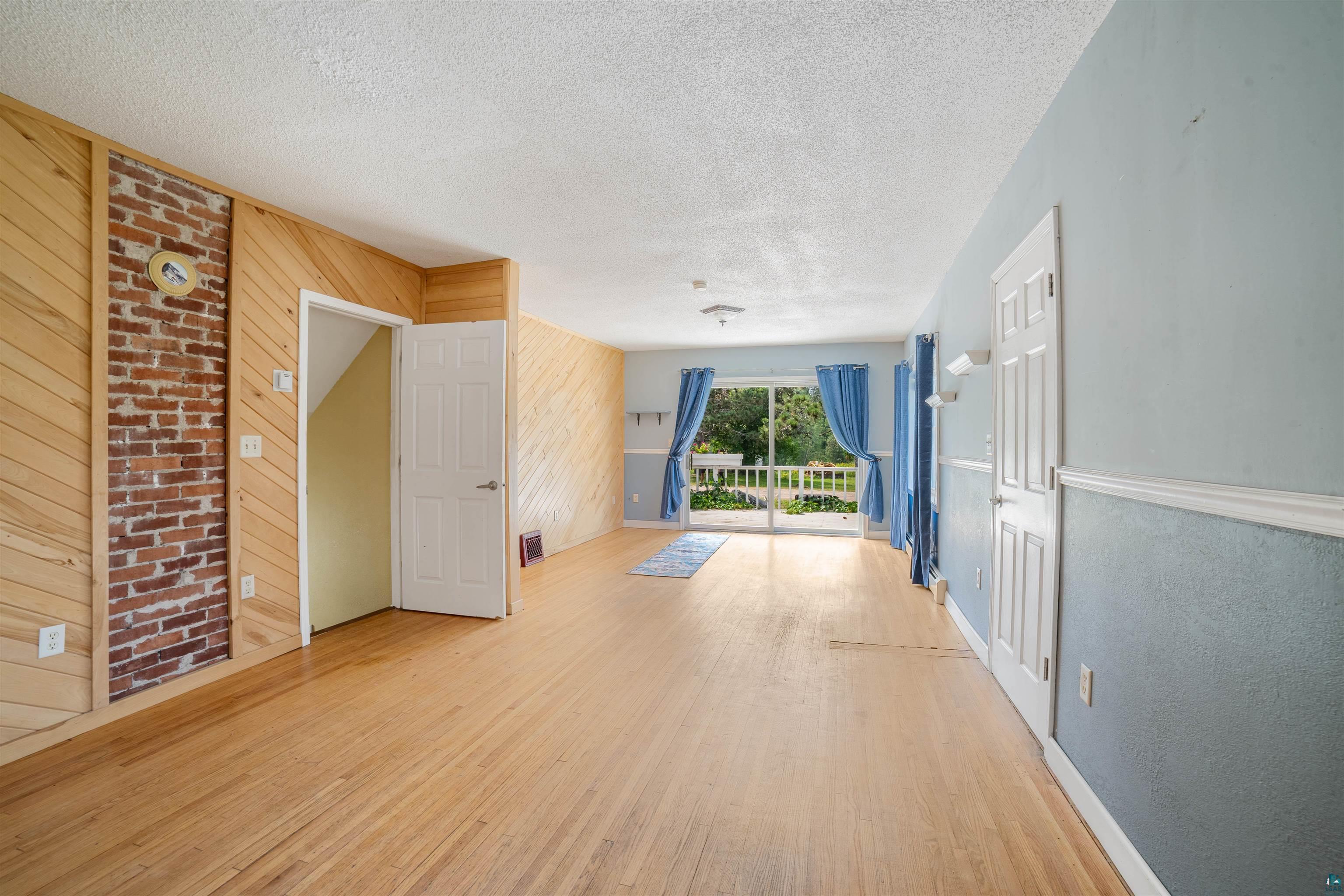 9372 McCamus Road Brookston, MN 55711 - Photo 18 of 49 Unfurnished living room with wooden walls, a textured ceiling, and wood finished floors