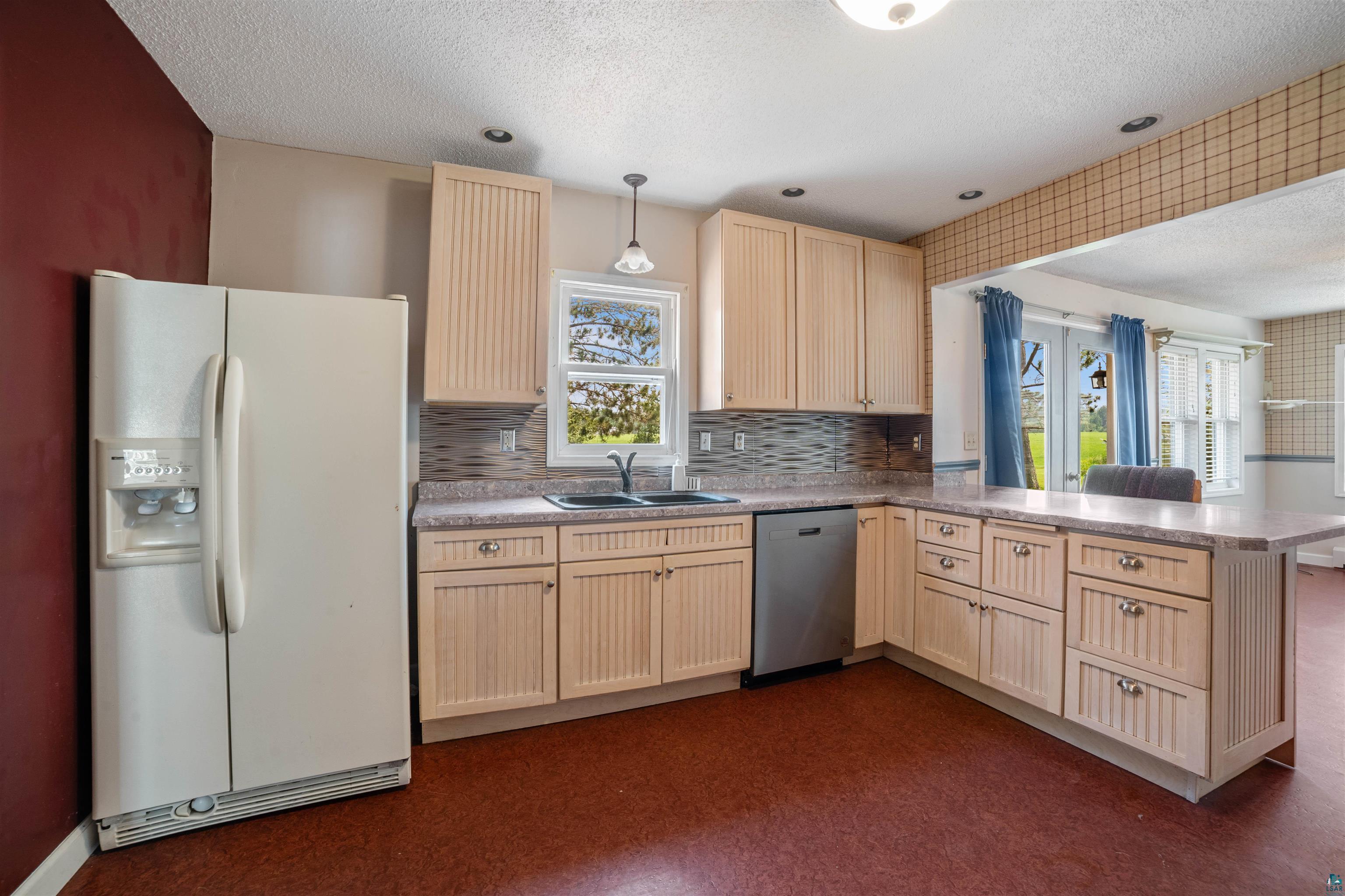 9372 McCamus Road Brookston, MN 55711 - Photo 23 of 49 Kitchen with light brown cabinetry, white refrigerator with ice dispenser, a peninsula, a textured ceiling, and dark floors