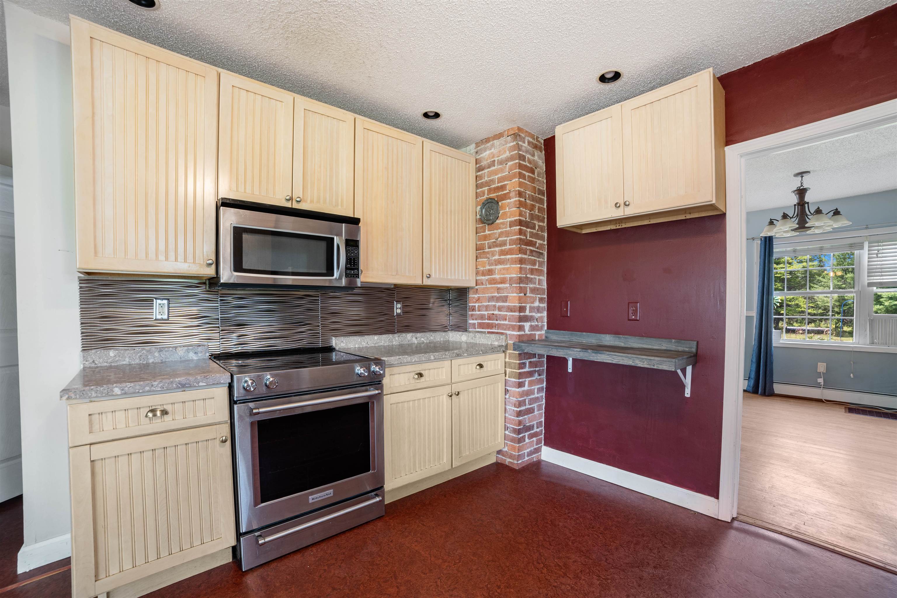 9372 McCamus Road Brookston, MN 55711 - Photo 24 of 49 Kitchen featuring appliances with stainless steel finishes, a textured ceiling, backsplash, light brown cabinets, and cream cabinets