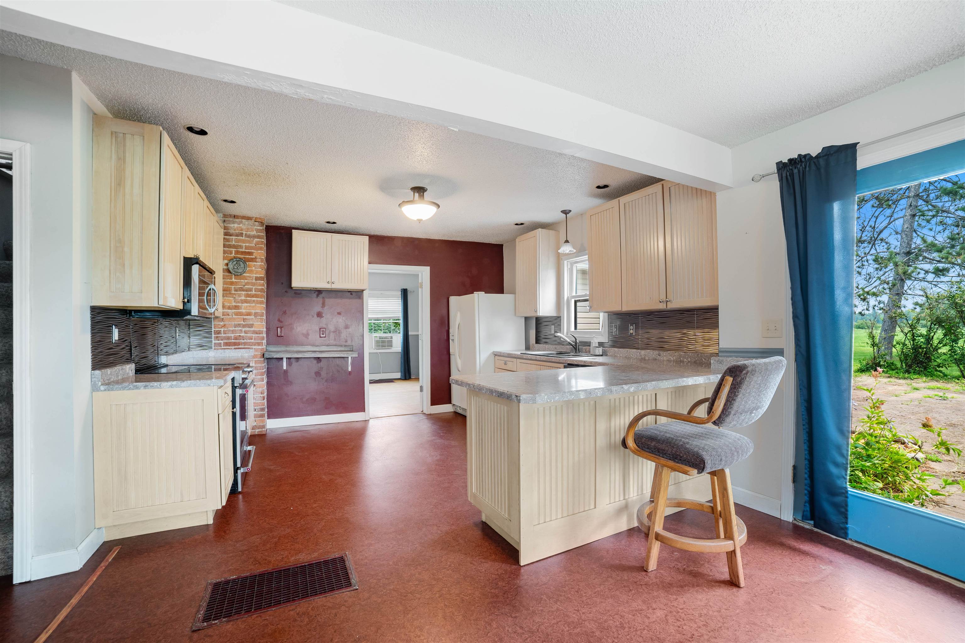 9372 McCamus Road Brookston, MN 55711 - Photo 25 of 49 Kitchen featuring decorative backsplash, a peninsula, a textured ceiling, appliances with stainless steel finishes, and a breakfast bar area