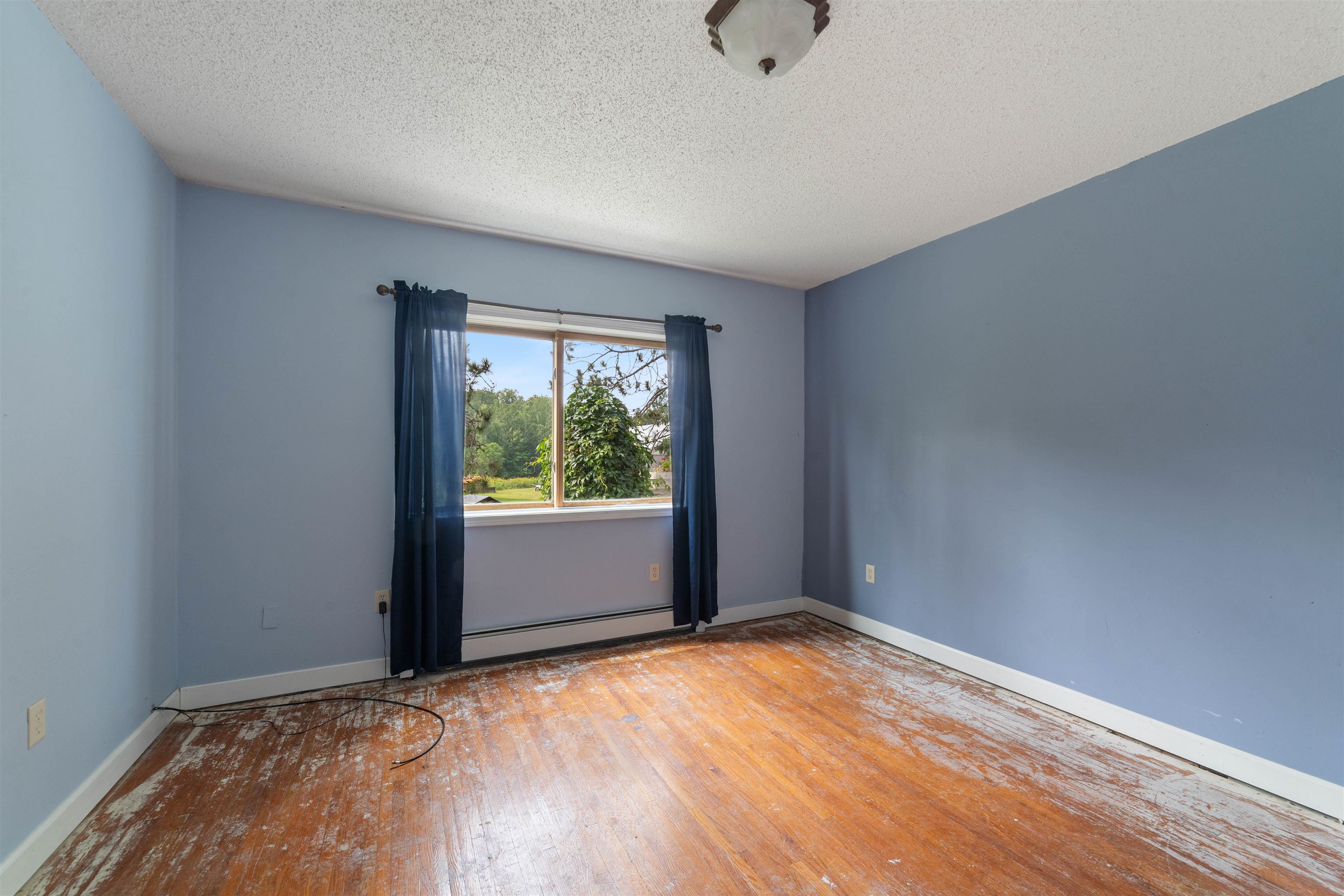 9372 McCamus Road Brookston, MN 55711 - Photo 27 of 49 Unfurnished room featuring a textured ceiling, wood finished floors, and baseboard heating