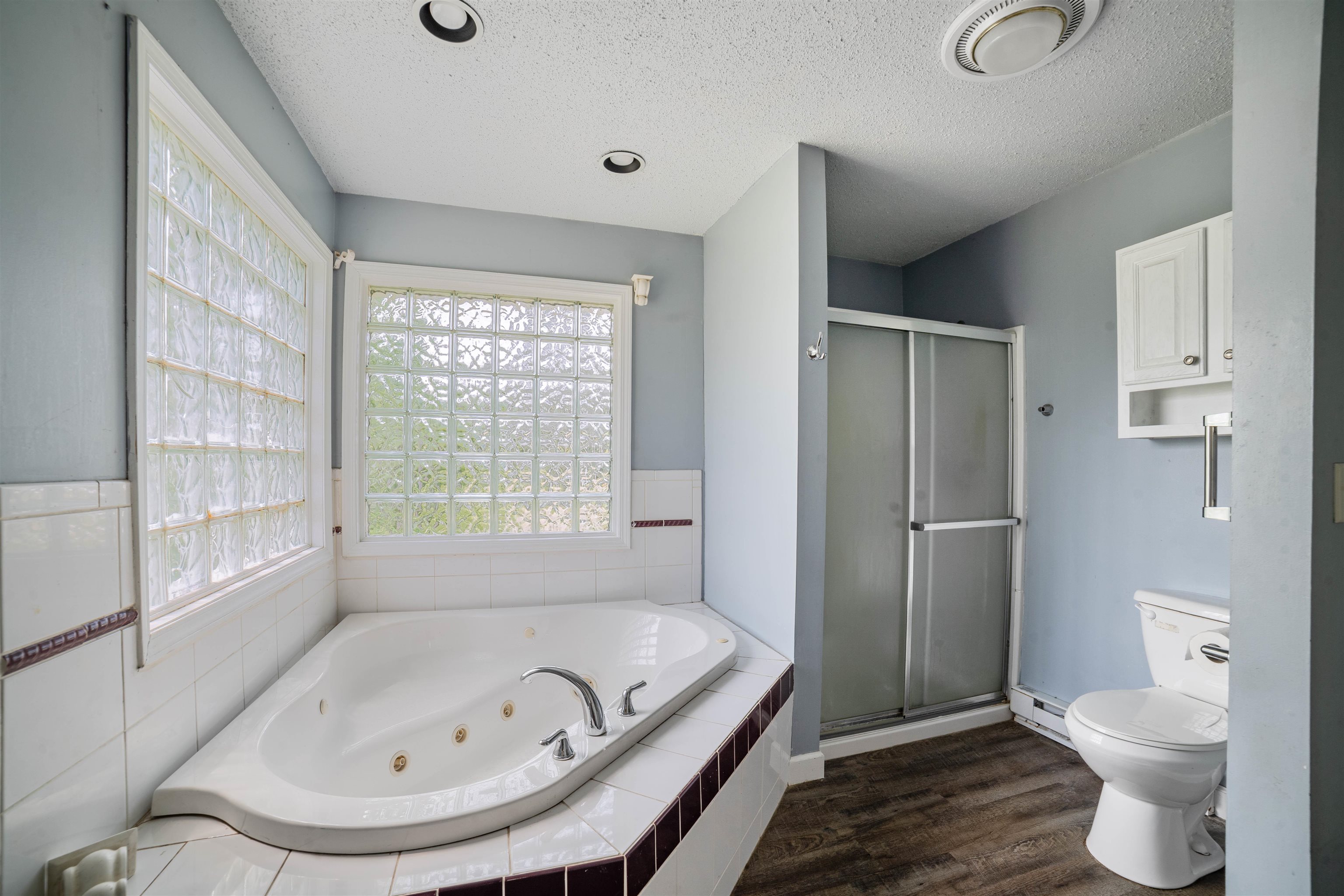 9372 McCamus Road Brookston, MN 55711 - Photo 28 of 49 Bathroom with a textured ceiling, a tub with jets, wood finished floors, a shower stall, and a baseboard heating unit