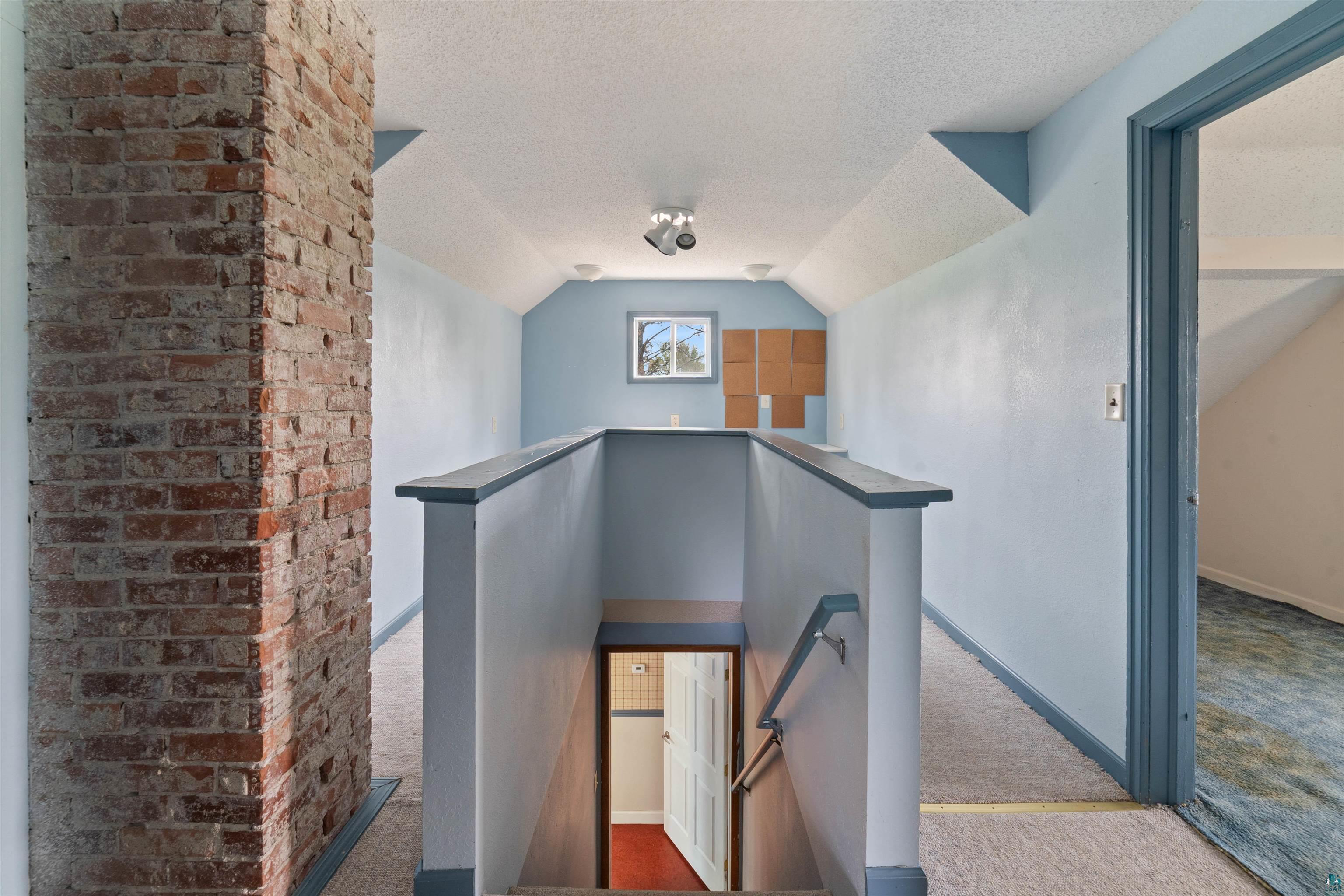 9372 McCamus Road Brookston, MN 55711 - Photo 34 of 49 Stairway with carpet floors, lofted ceiling, and a textured ceiling
