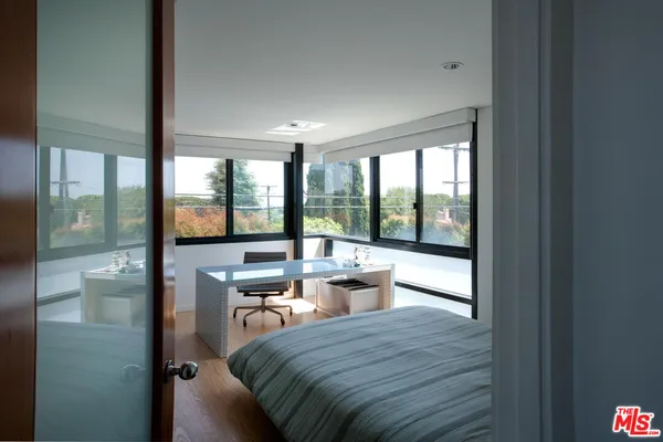 a room with a bed and large windows
