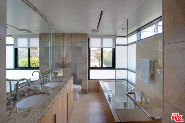 a bathroom with a granite countertop sink a mirror and a shower