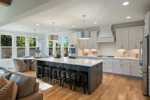 a large kitchen with cabinets chairs and wooden floor