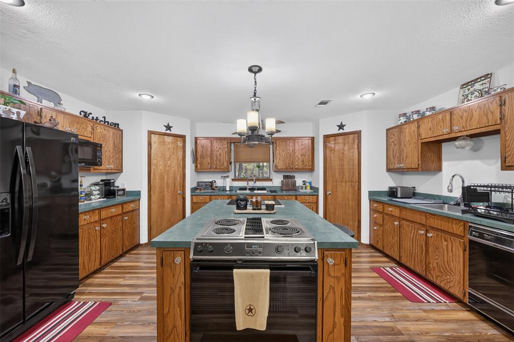 10964 River Ranch Road Kemp, TX 75143 - Photo 18 of 40 Expansive kitchen featuring wood-finish flooring, abundant wood cabinetry, a central island with built-in cooktop, and a double basin sink
