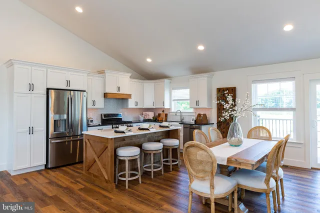 a dining room with stainless steel appliances a dining table and chairs