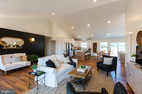 a living room with stainless steel appliances furniture a rug and a kitchen view