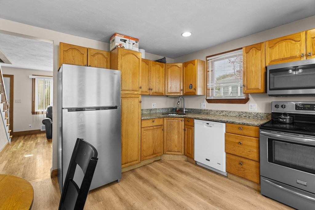 19-21 Bursley Road Weymouth, MA 02191 - Photo 7 of 33 a kitchen with granite countertop a refrigerator a stove top oven cabinetry a sink and a window