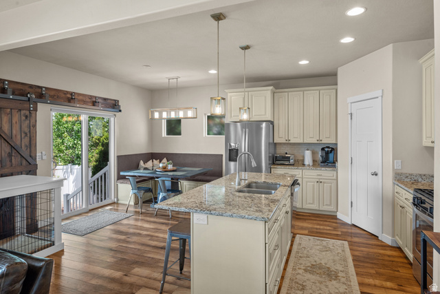 955 Delorean Lane Midvale, UT 84047 - Photo 11 of 47 Open-concept kitchen featuring an island with an undermount sink, granite countertops, and light-toned cabinetry