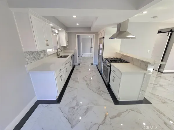 a large white kitchen with stainless steel appliances granite countertop a sink and cabinets